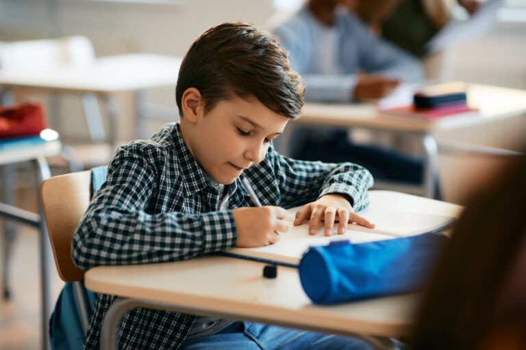 Elementary student writing during a class in the classroom.