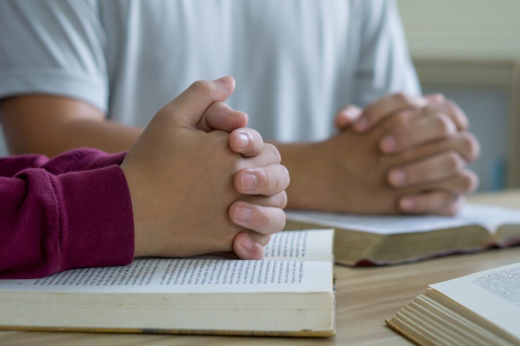 Prayer meeting concept.Colleagues shaking hands reading scriptur