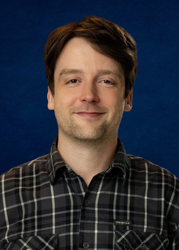 Andrew Gettis portrait with a slight smile against a blue background.